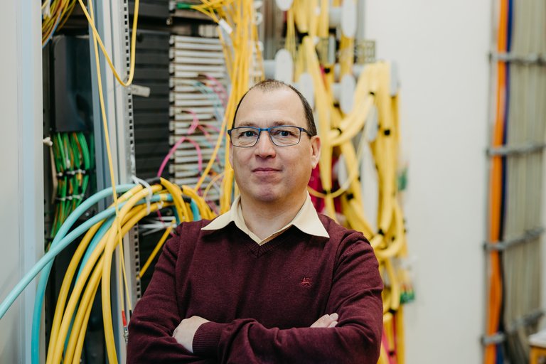 Gregor Zimmermann, IT Leiter der OVGU, vor dem Serverraum, aus dem diverse Kabel kommen