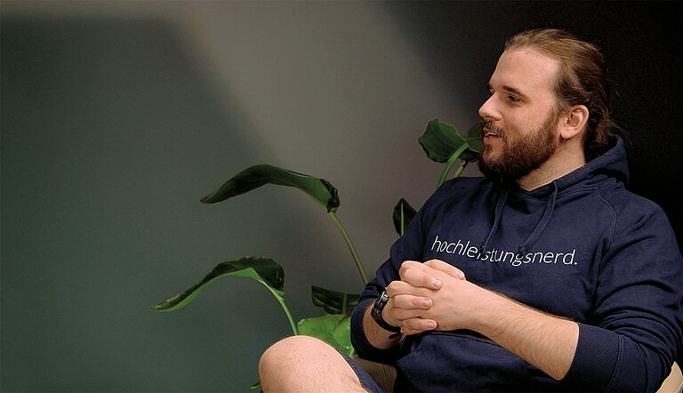 Daniel Menzel von Menzel IT GmbH beim Interview neben einer Pflanze, gestikulierend