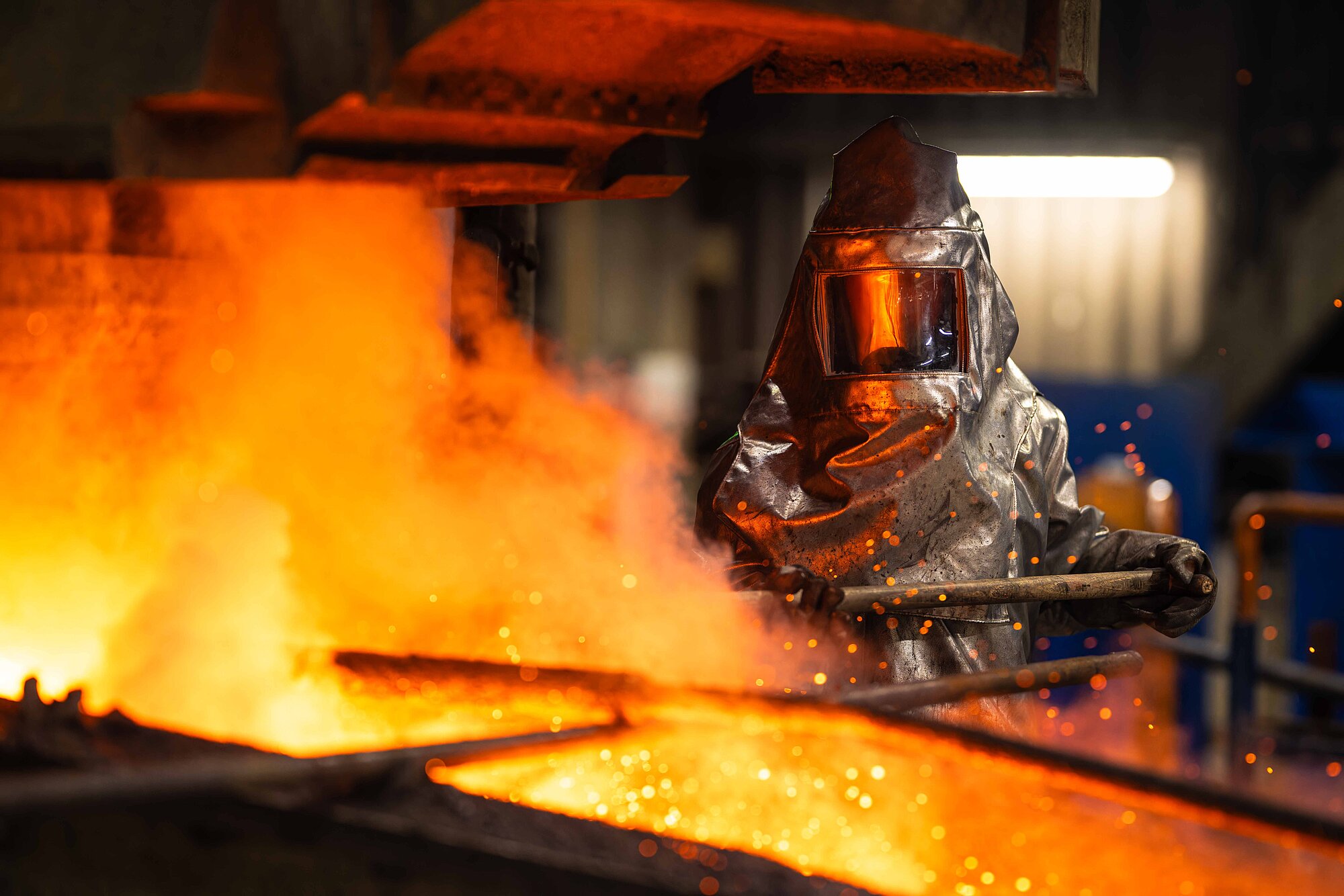 Worker in protective gear working steel in a fire