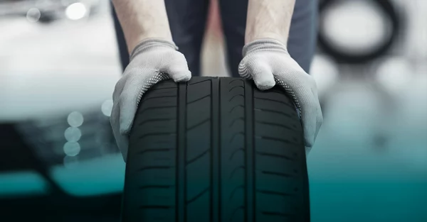 A car tire rolled forward by a person wearing gloves
